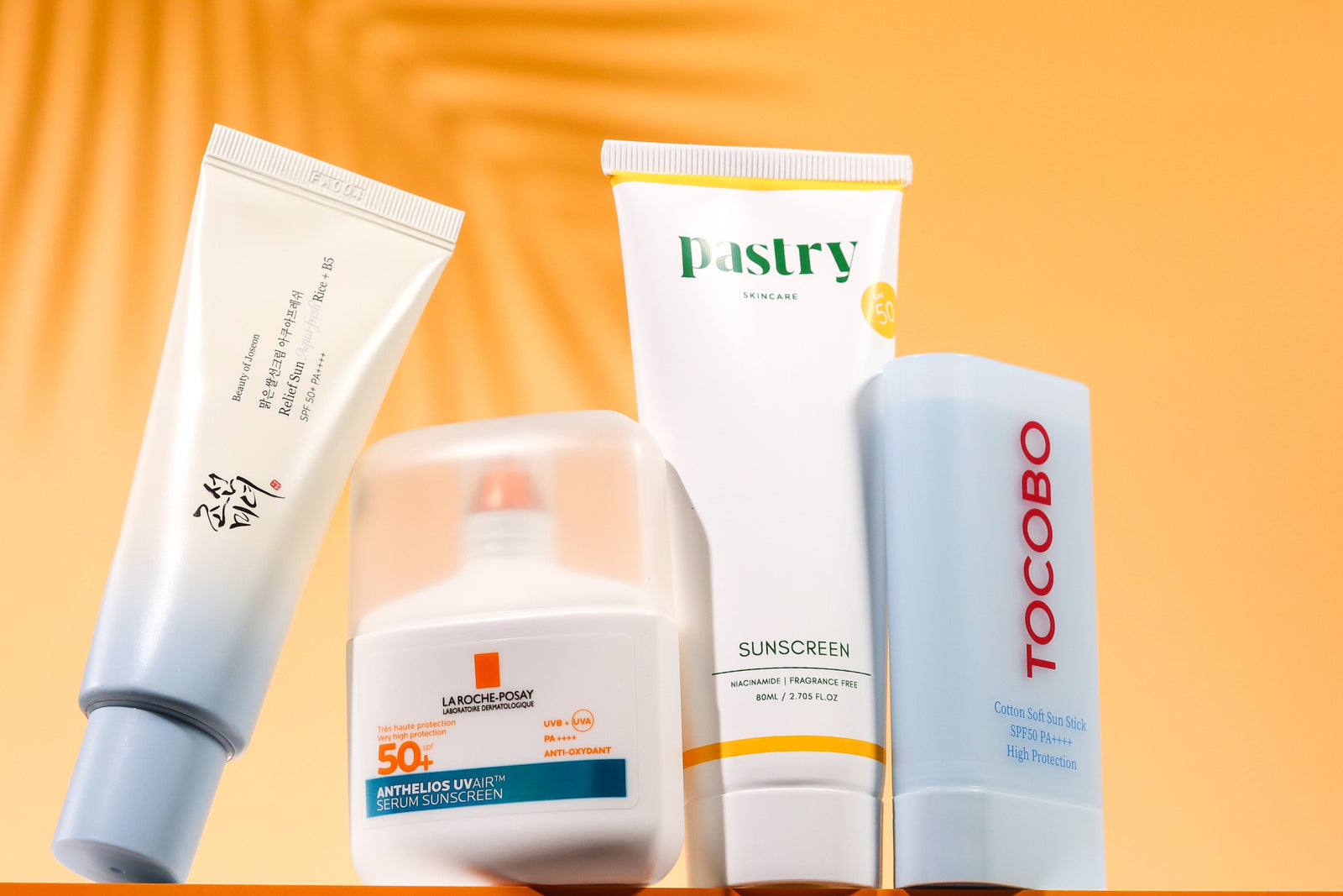 Beauty of Joseon Relief Sun, La Roche-Posay Anthelios UVAIR, Pastry niacinamide sunscreen, and TOCOBO Cotton Soft sun stick on orange.