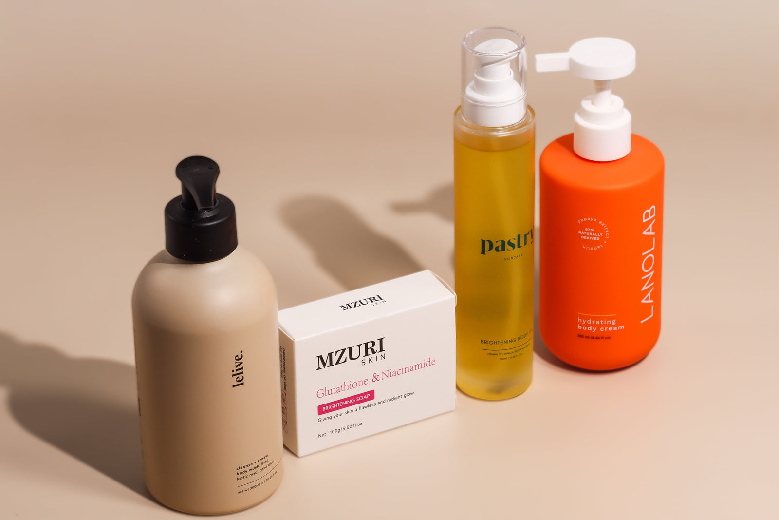 Lelive Clean Slate body wash, Mzuri Skin glutathione and niacinamide soap, Pastry brightening body oil, and Lanolab hydrating body cream on beige.